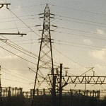 A pylon next to a railway line and gas cylinders.